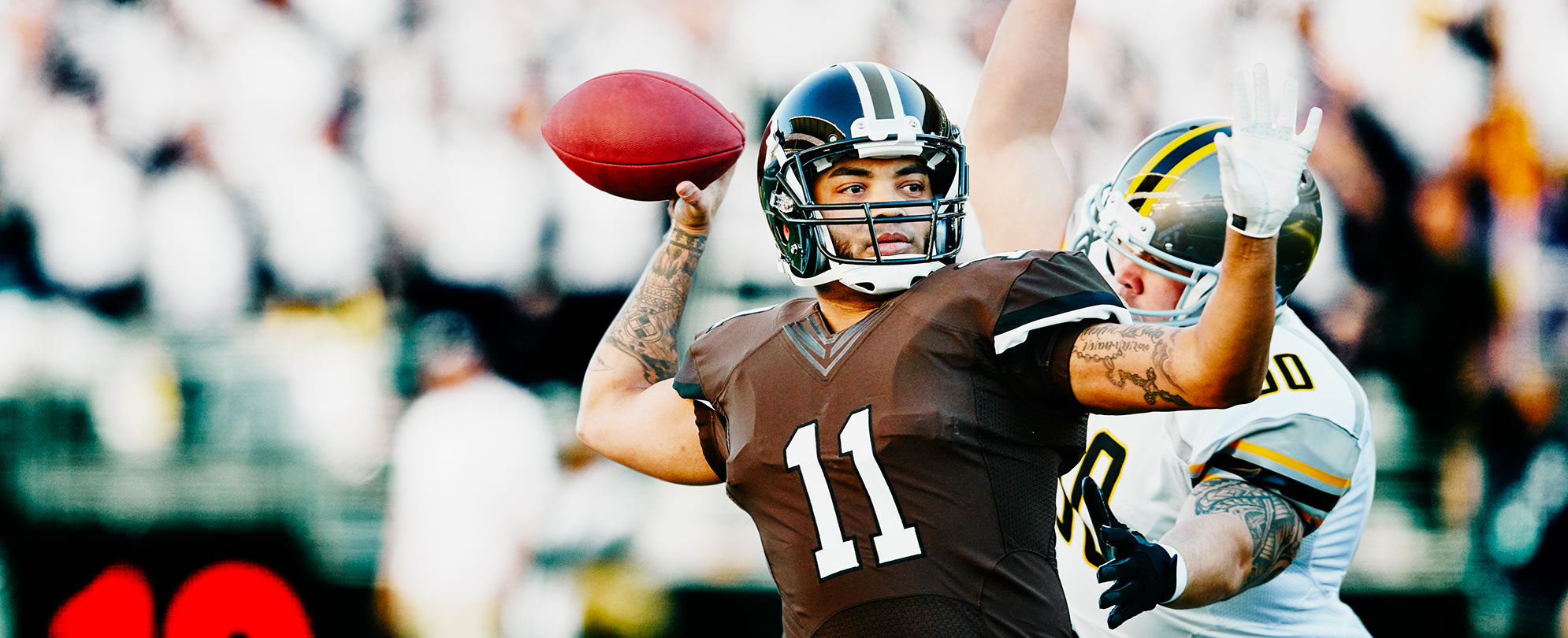 A football player throwing a football and an opposing player preparing to tackle