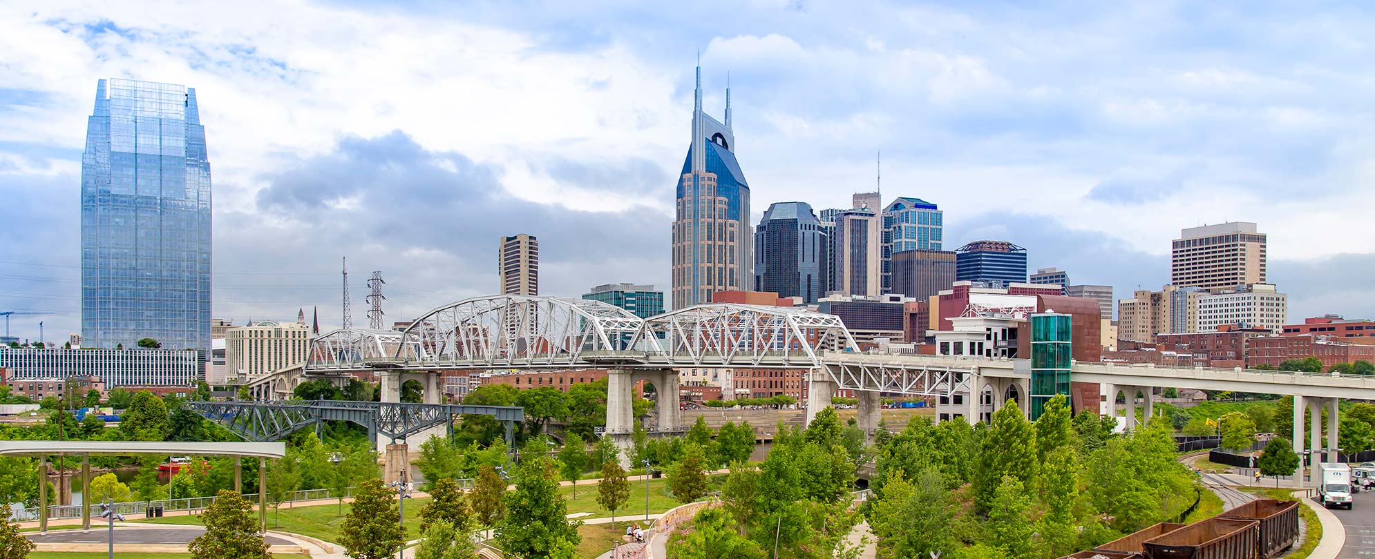 The pedestrian bridge and city skyline of Nashville, Tennessee on a clear, sunny day.