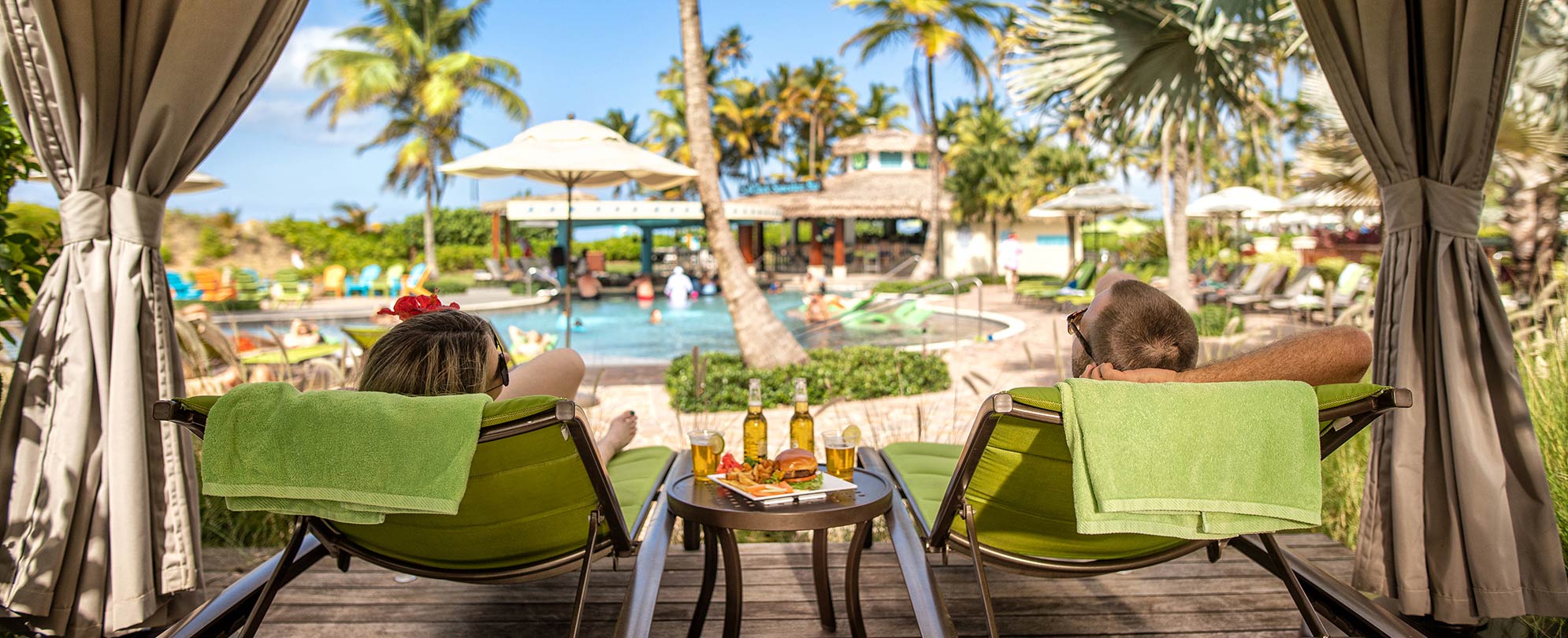 Man and woman relaxing on green pool chairs at a Margaritaville Vacation Club timeshare resort pool.