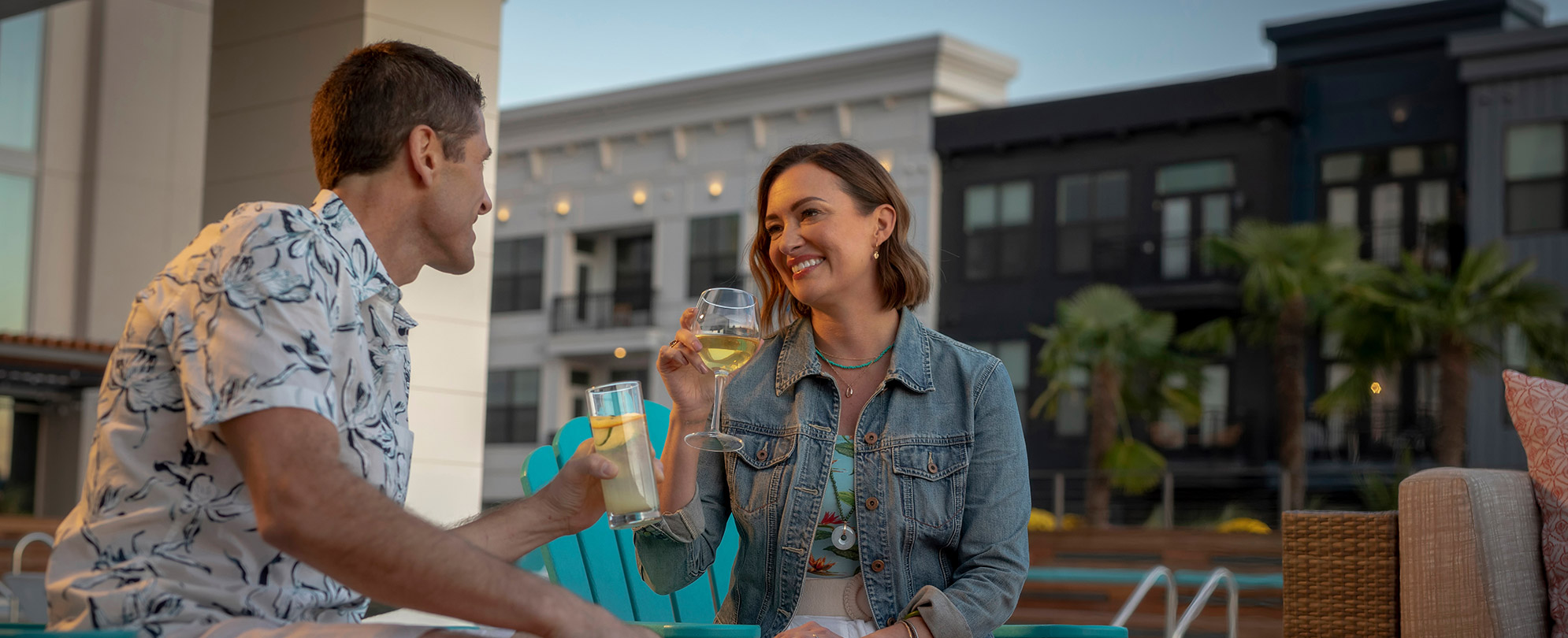 Man and woman sit in adirondek chairs each holding a drink while staying at a Margaritaville Vacation Club resort.