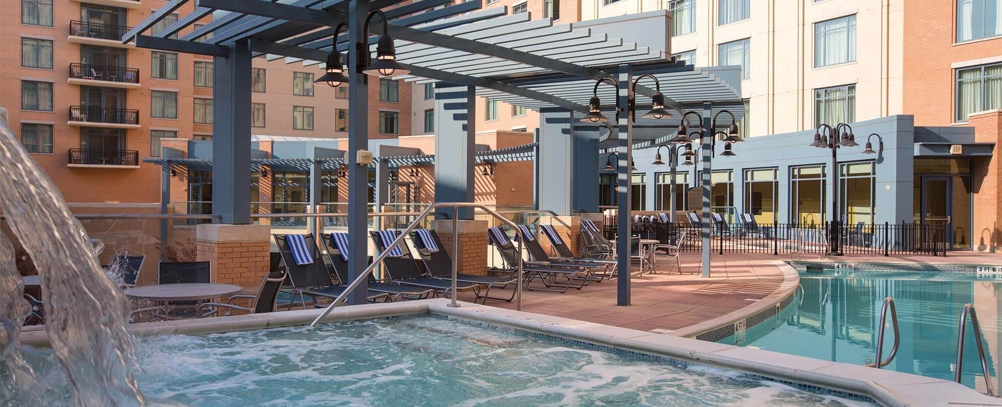 Jetted hot tub and pool chairs under an awning at a Margaritaville Vacation Club resort pool.