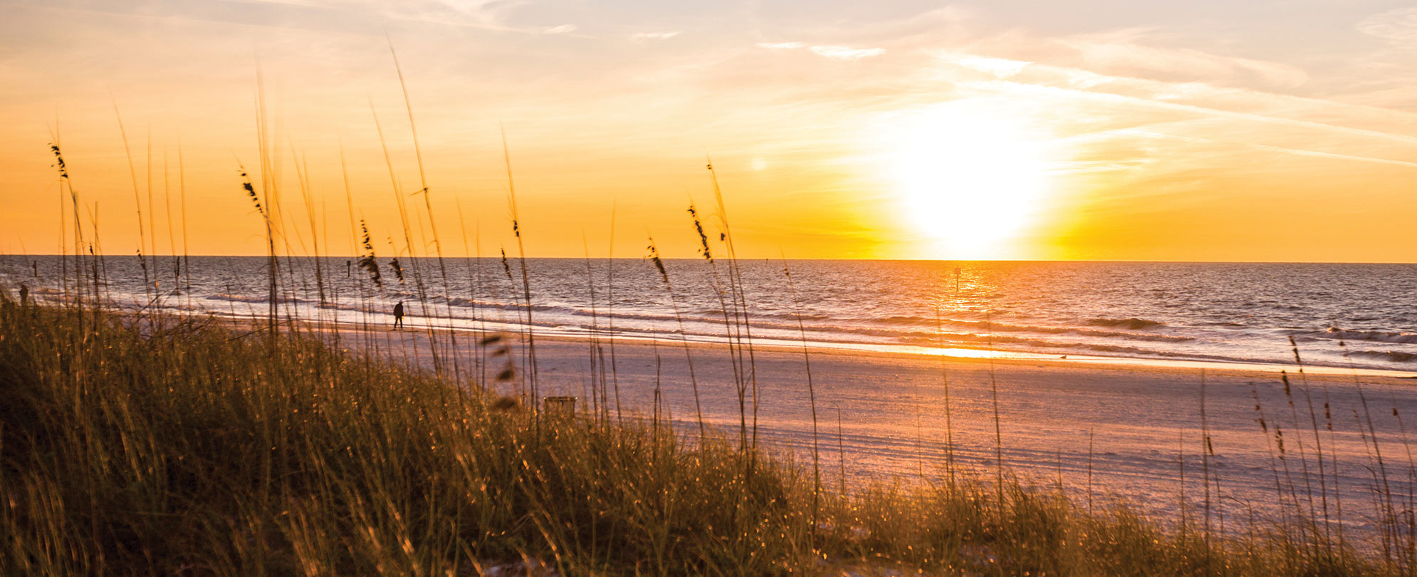 A man walks along the beach at sunrise in Pompano Beach, Florida