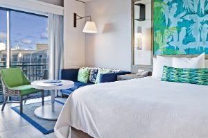 Blue couch and king bed with white linens in a studio suite at Margaritaville Vacation Club by Wyndham - Rio Mar.