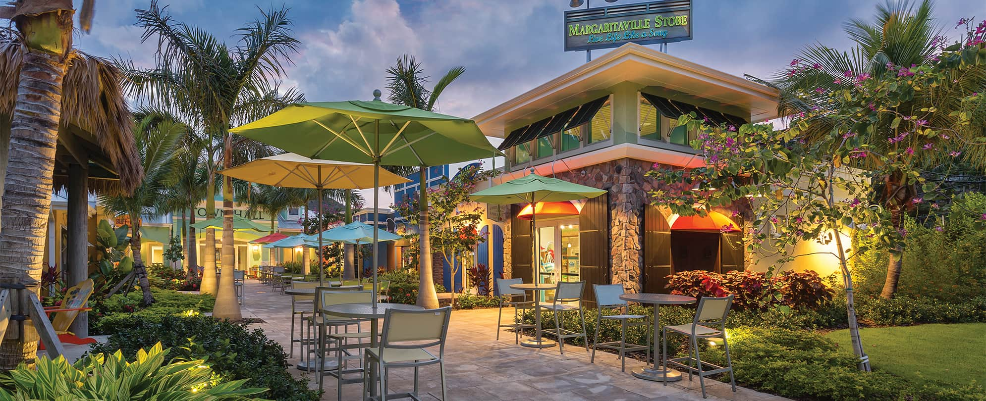 Outdoor tables and chairs in front of Margaritaville Store at night at Margaritaville Vacation Club by Wyndham - St. Thomas.